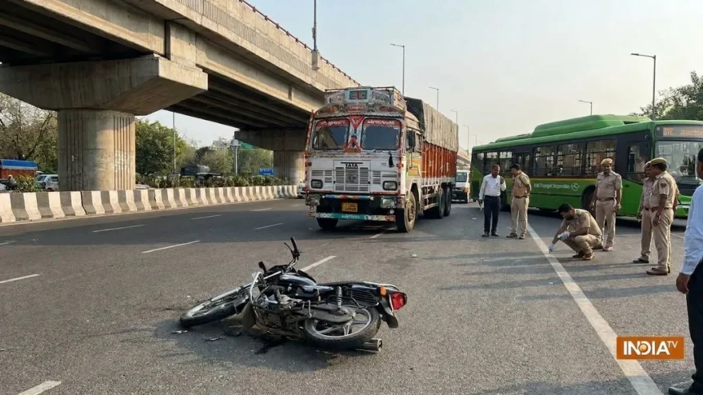 दिल्ली में सड़क पार कर रही DTC बस मार्शल को बाइक ने मारी टक्कर, ट्रक की चपेट में आने से मौत